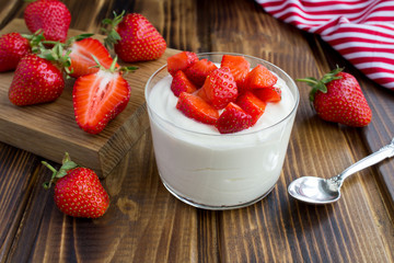 Milk yogurt with strawberry on the brown wooden background