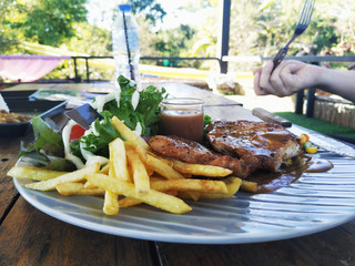 Steak with fresh salad and light dishes served on a white plate.
