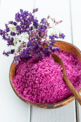 Sea salt in bowl, aroma oil in bottles, Wellness and flowers on grey textured background and flowers on vintage wooden background. Selective focus.