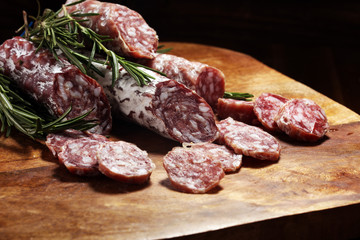 thinly sliced salami sausages on a wooden texture on the background.