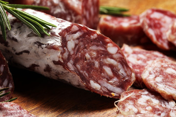 thinly sliced salami sausages on a wooden texture on the background.