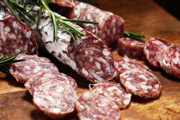 thinly sliced salami sausages on a wooden texture on the background.
