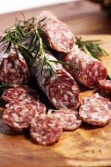 thinly sliced salami sausages on a wooden texture on the background.