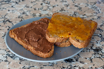Slice toast with cocoa cream and peach jam on blue plate