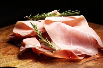 Sliced ham on wooden background. Fresh prosciutto cotto. Pork ham sliced with herbs