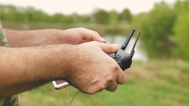Remote control drone in the male hands of the pilot close-up. Man navigation flying drone with remote control. Man in nature in the countryside.