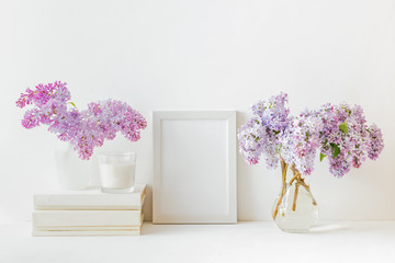 Home interior with decor elements. White frame, branches of lilac in a vase, interior decoration