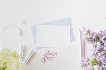 Mockup white greeting card and envelope with branches of lilac on a light background