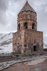 Fototapeta na wymiar gergeti chapel watch tower in front of mountain