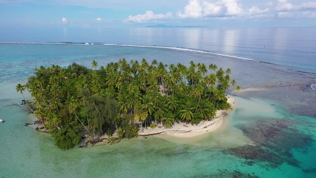 Tropical island paradise - Aerial drone video from French Polynesia of Motu Mahaea, Tahaa, Tahiti. Aerial view of atoll with palm trees, turquoise blue water in coral reef lagoon, South Pacific Ocean.