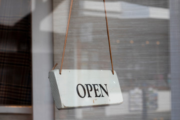 Open for business sign on shop door glass to retail premises