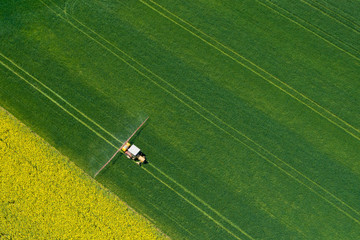 Aerial view of farming tractor plowing and spraying on field.  Agriculture. View from above. Photo...