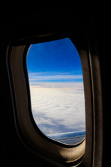 Obraz na płótnie Canvas View of blue sky with white clouds through the porthole window flying airplane