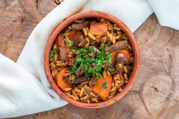 Giouvetsi - traditional Greek baked dish with beef and orzo pasta in tomato sauce - top view.