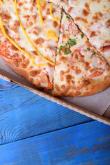 Set of different pieces of pizza in a carton box on blue table. Ordering food home