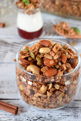 Granola with different nuts in a glass jar on the white wooden table