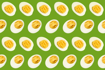 Rows of many halves of boiled eggs on a green background