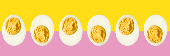 Row of boiled egg halves on a pink and yellow background - Powered by Adobe