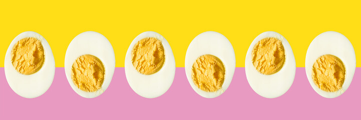 Row of boiled egg halves on a pink and yellow background