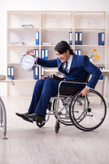 Young male employee in wheelchair working in the office 