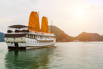 Cruise traditional ship wooden junk golden sailing Ha Long Bay, Vietnam UNESCO World Heritage Site.