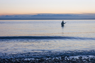 A fisherman and Puget Sound gulf at mountain background