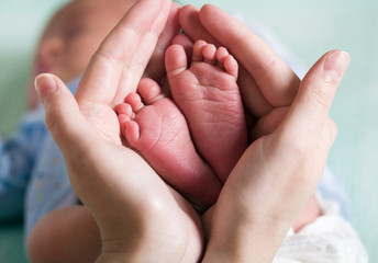 Obraz na płótnie Canvas baby feet in mom's hands concept tenderness care (macro)