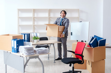 Young man employee with boxes in the office 