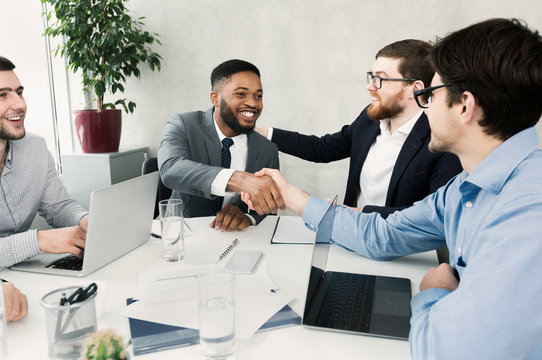 Happy Team Congratulating Successful Worker By Shaking Hands