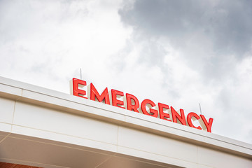 The bold and highly visible red letters of the "emergency" sign by the main entrance access of a hospital.