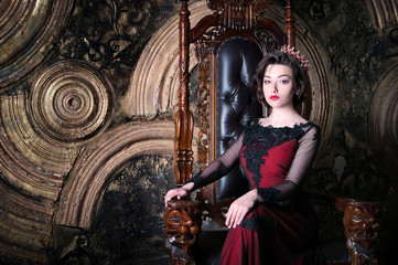 Queen in red dress sitting on throne. Symbol of power