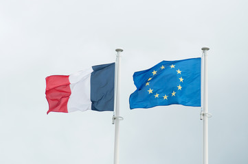 closeup of french and european flags floating on grey sky background