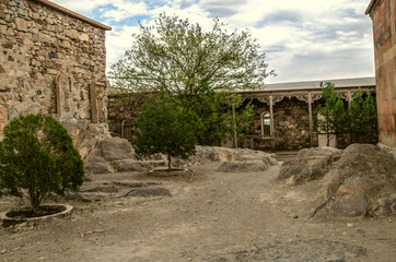 Fototapeta na wymiar The courtyard of the medieval fortress of Khor Virap with living quarters, khachkars by the wall and trees growing among the stones