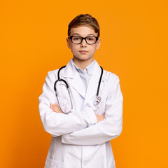 Confident teen boy in doctor uniform posing with arms folded