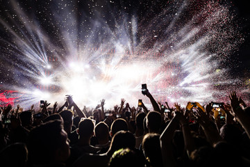 Confetti fireworks above the crowd on music festival. - obrazy, fototapety, plakaty