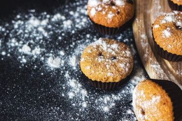 Homemade cupcakes with sugar powder on a black background. Selective focus, top view, copy space.