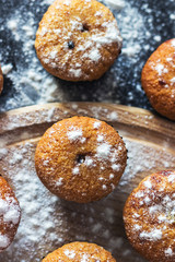 Homemade cupcakes with sugar powder on a black background. Selective focus, top view.