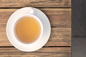 Close up of a cup of tea on a wooden table resting on a gray stone floor. Top view with copy space.