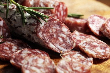 thinly sliced salami sausages on a wooden texture on the background.