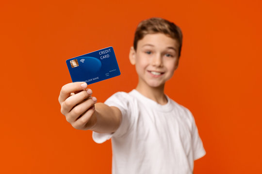 Smiling boy showing credit card at camera