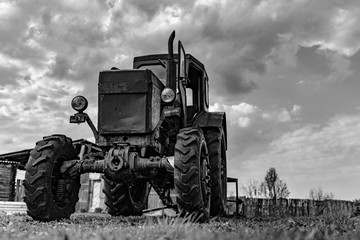 Fototapeta na wymiar An old broken tractor stands on an abandoned farm. Bankruptcy farm.