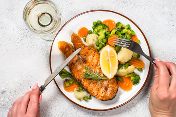 Woman eating Grilled salmon  steak with vegetables.
