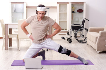 Fototapeta premium Injured young man doing exercises at home 