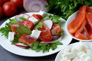 Fresh salad from salmon and vegetables on a white plate.