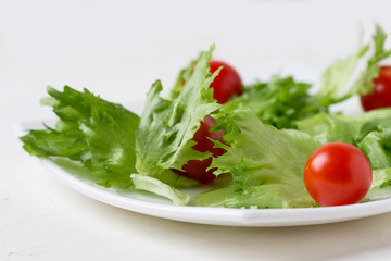 Fresh lettuce and cherry tomatoes on a white plate.