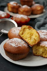 Homemade muffins with pineapple pieces, sprinkled with powdered sugar, are located on a dark background
