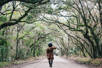 Girl Walking Under Tree Canopy on Dirt Road Through Swamp on Edisto Island in South Carolina 