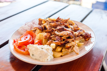 Greek gyros with french fries, vegetables and tzatziki sauce on white plate