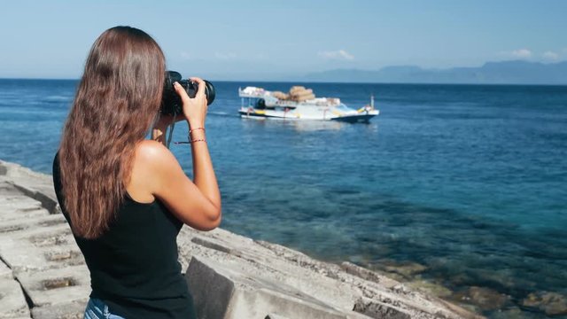 Side view of girl photographer takes pictures of boat on professional camera