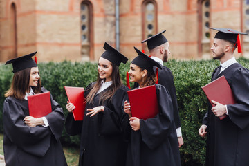 Portrait of graduate school kids standing with degree scroll in campus at school